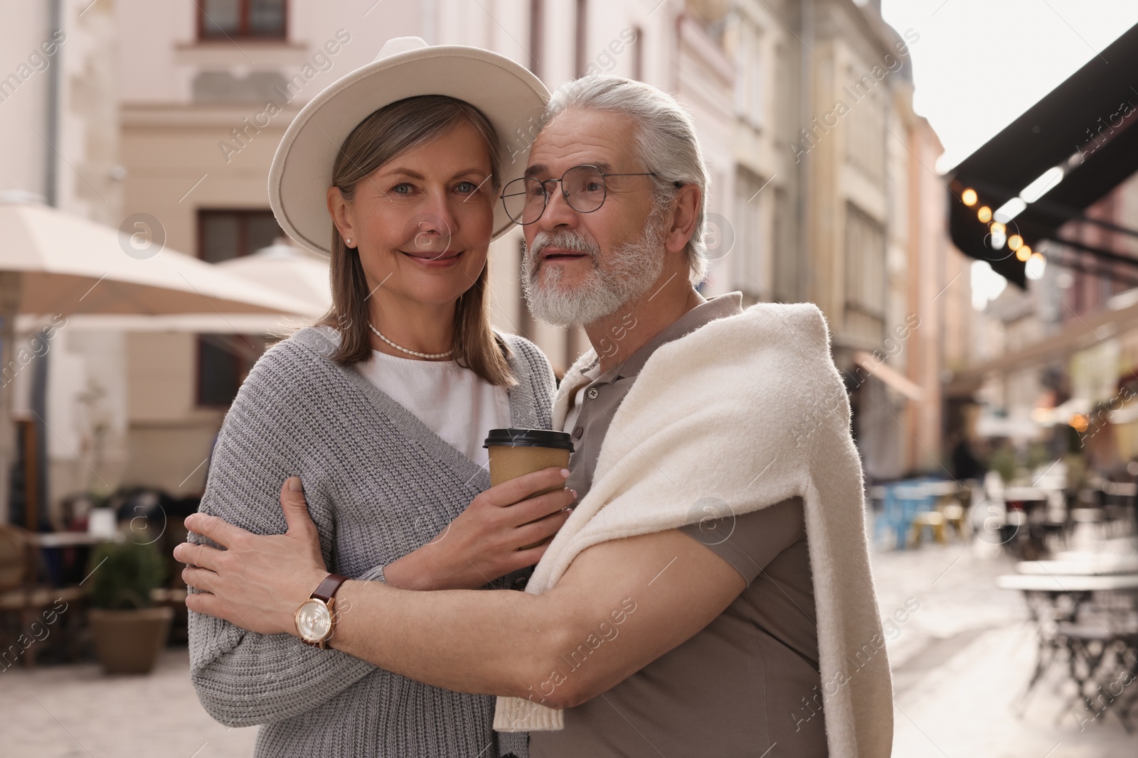 Photo of Affectionate senior couple with coffee walking outdoors