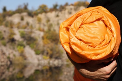 Photo of Man with orange sleeping bag outdoors, closeup. Space for text
