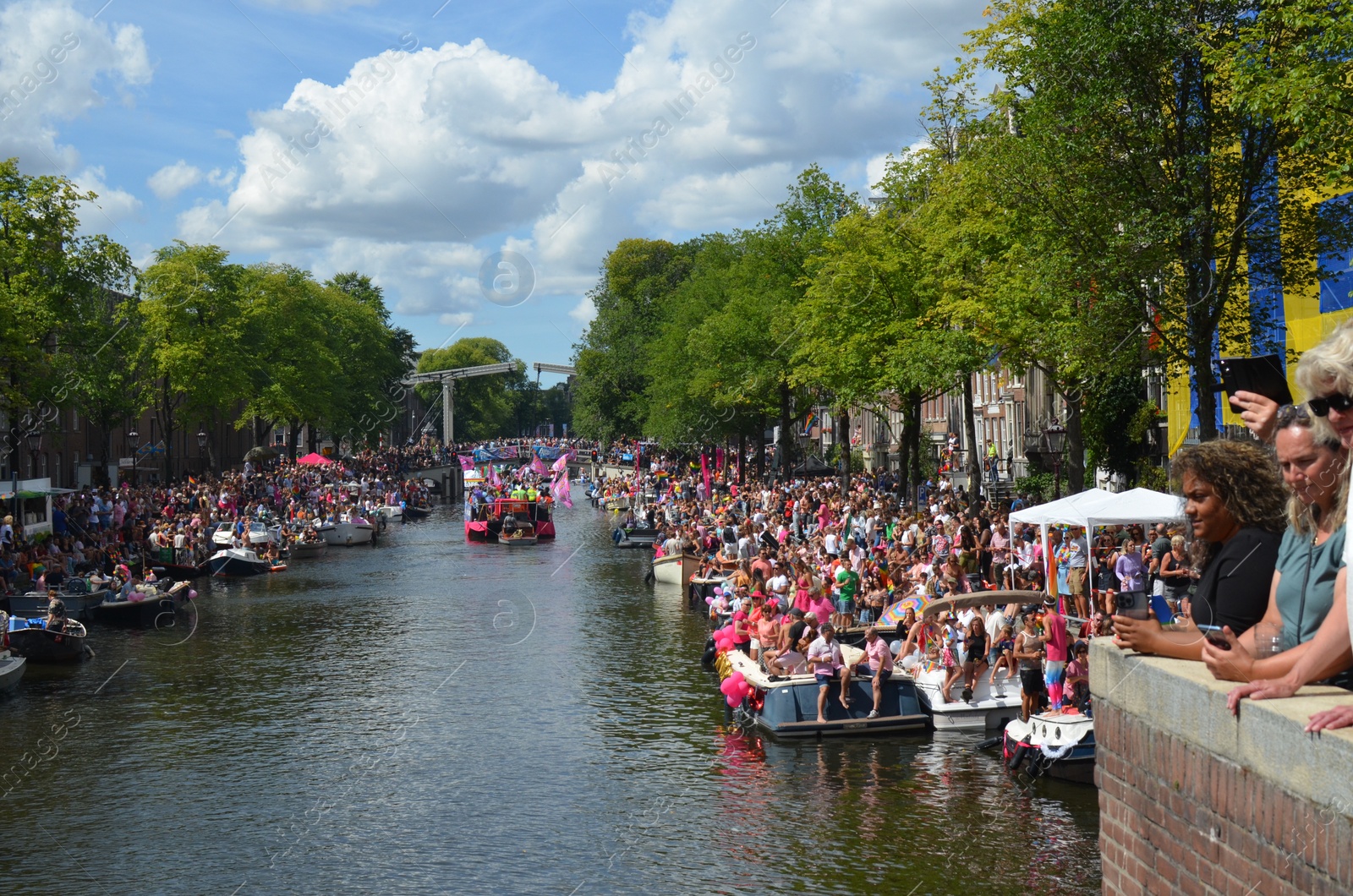 Photo of AMSTERDAM, NETHERLANDS - AUGUST 06, 2022: Many people in boats at LGBT pride parade on river