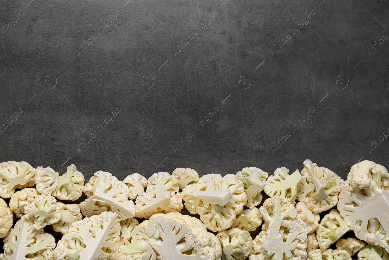 Photo of Cut fresh raw cauliflower on grey table, flat lay. Space for text