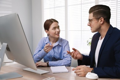 Businessman helping intern with work in office