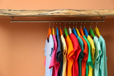 Photo of Rack with different child's clothes near coral wall, closeup