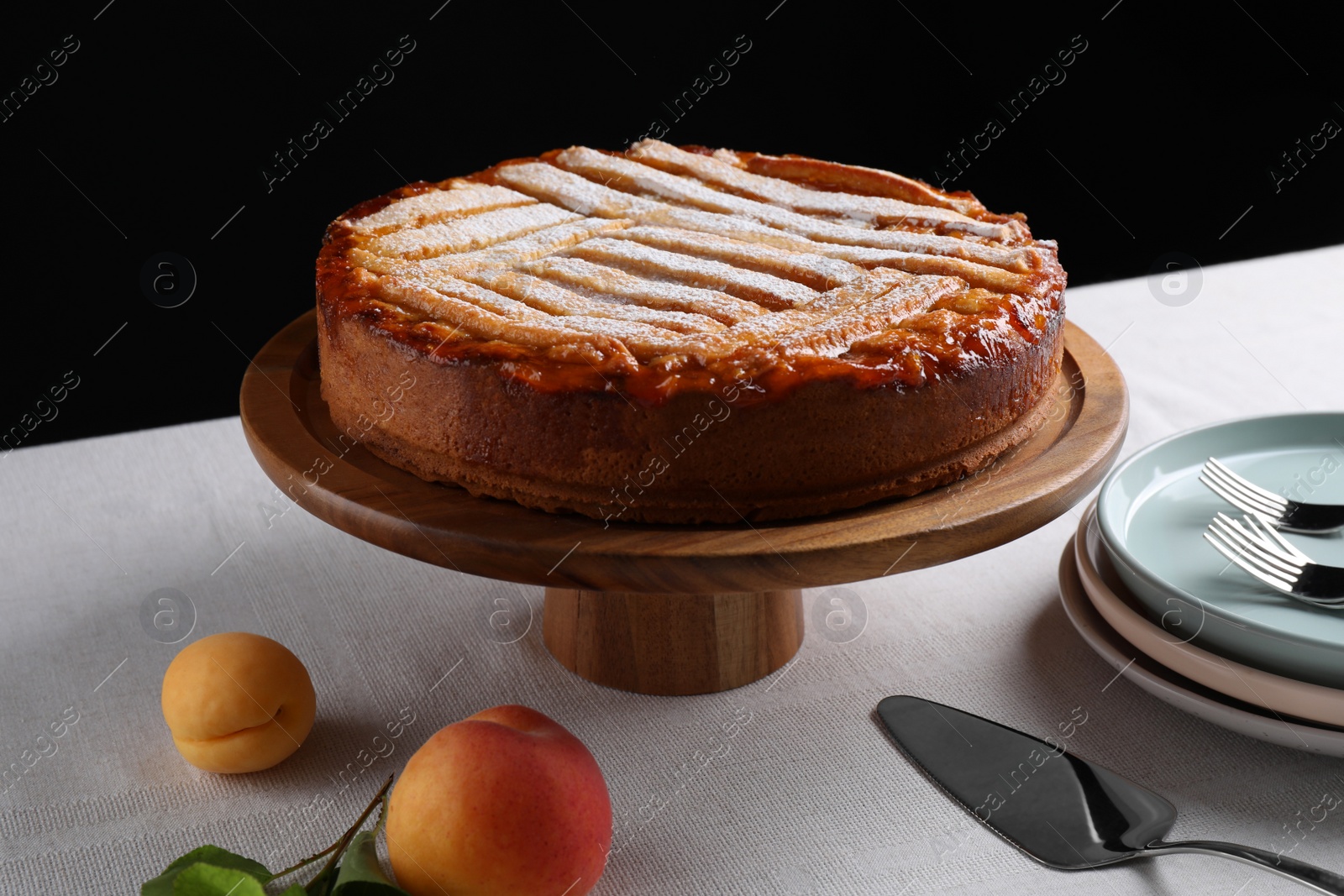 Photo of Tasty apricot pie with powdered sugar on table