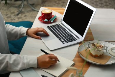 Blogger working with laptop in cafe, closeup