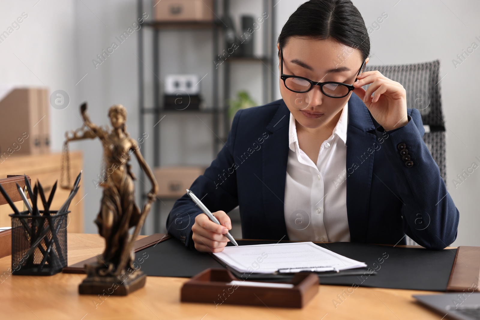 Photo of Notary signing document at table in office