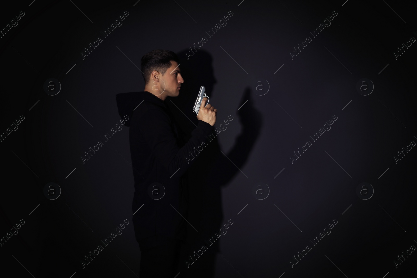 Photo of Professional killer with gun on black background. Space for text