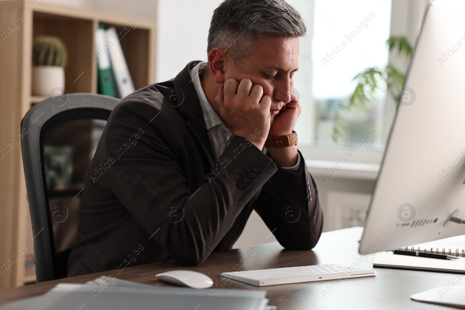 Photo of Man snoozing at wooden table in office