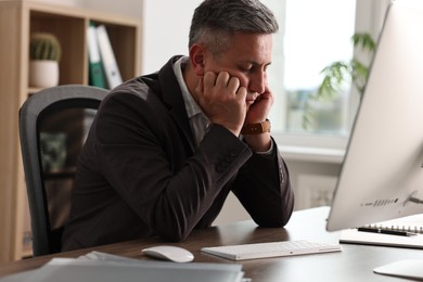 Man snoozing at wooden table in office