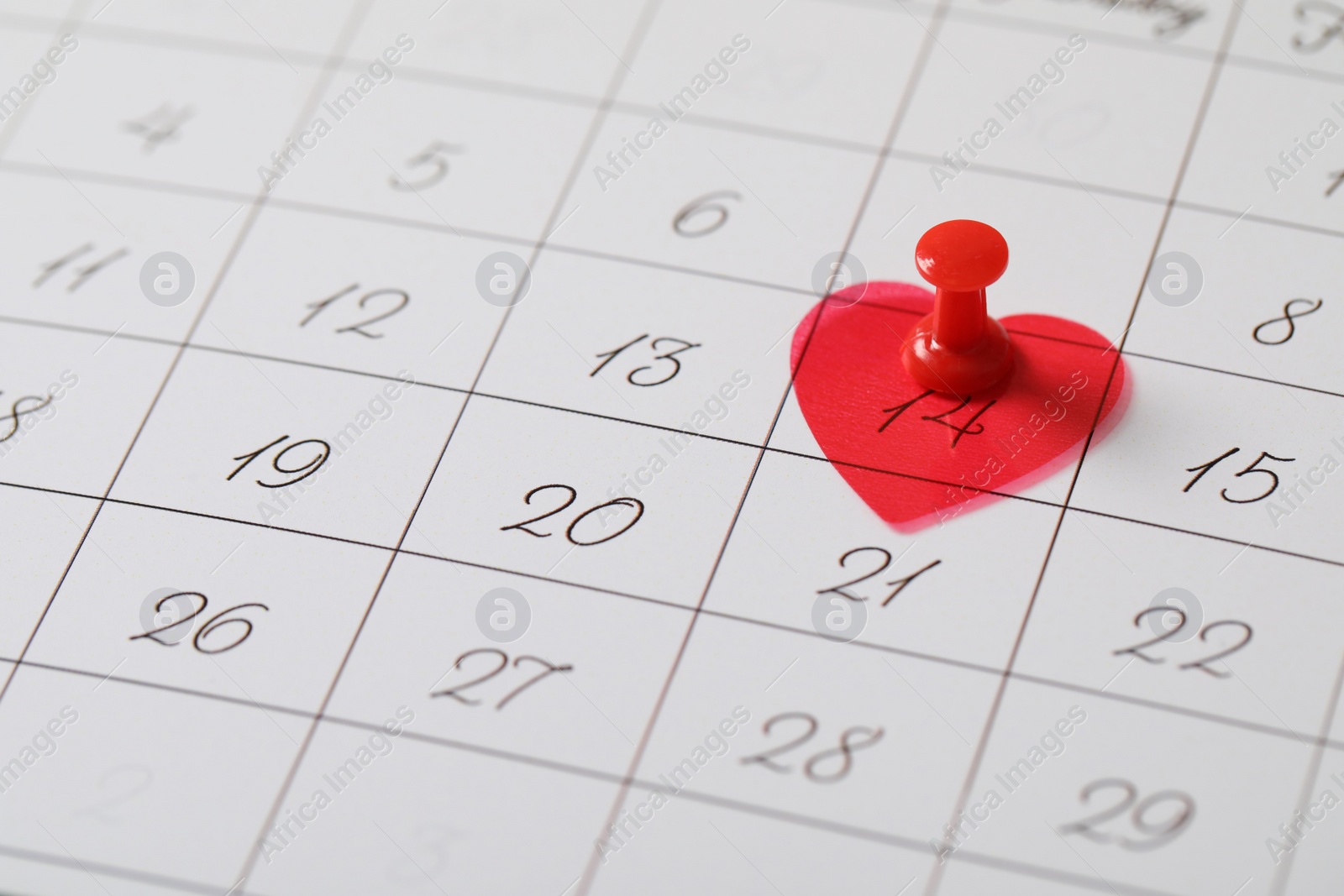 Photo of Calendar page with red pin and heart on Valentine's Day, closeup