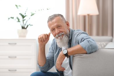 Photo of Portrait of handsome mature man sitting on sofa in room