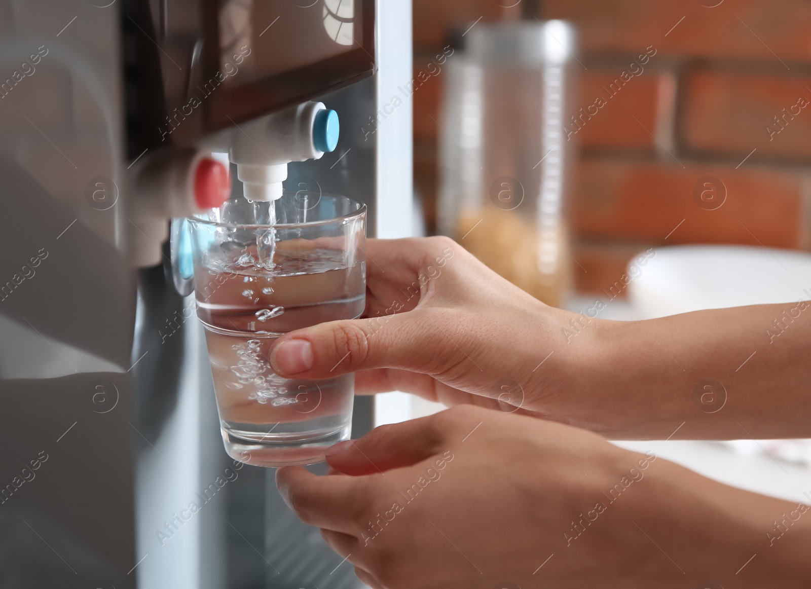 Photo of Woman filling glass with water from cooler indoors, closeup