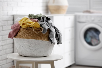 Wicker basket with dirty laundry indoors, space for text