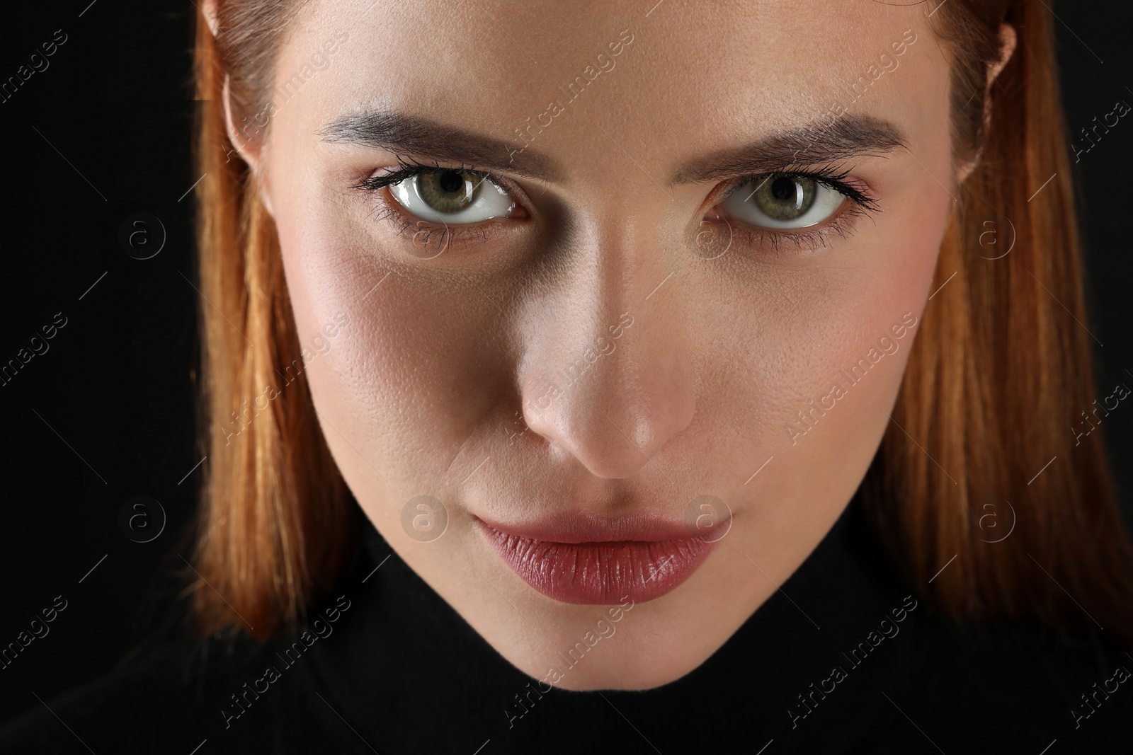 Photo of Evil eye. Young woman with scary eyes on black background, closeup