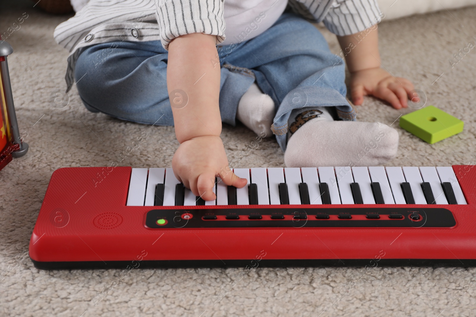 Photo of Little child playing toy piano indoors, closeup