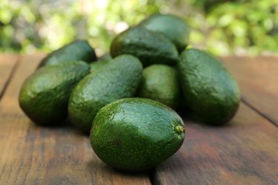 Many tasty ripe avocados on wooden table outdoors