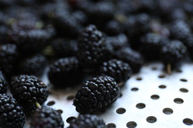 Photo of Heap of delicious ripe black mulberries in colander, closeup