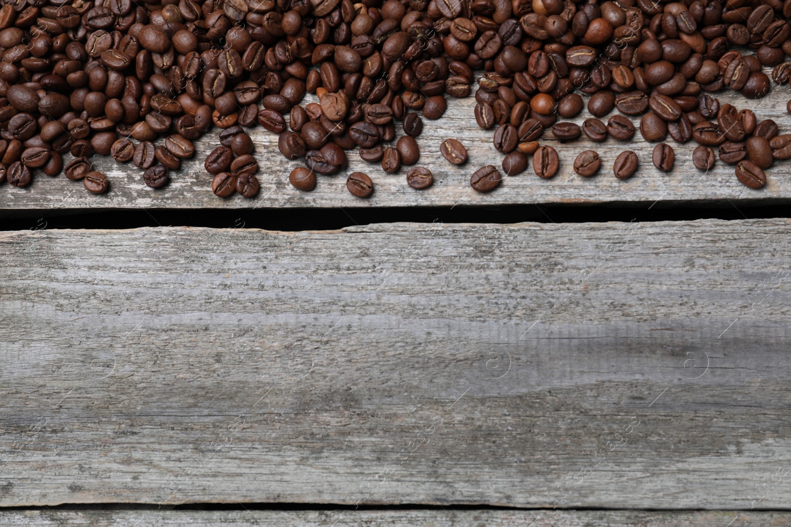 Photo of Roasted coffee beans on wooden table, flat lay. Space for text