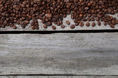 Roasted coffee beans on wooden table, flat lay. Space for text