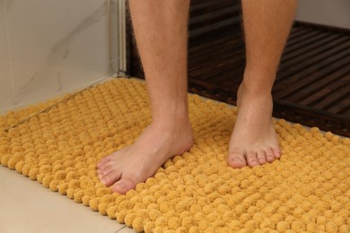 Man standing on soft mat near shower stall in bathroom, closeup