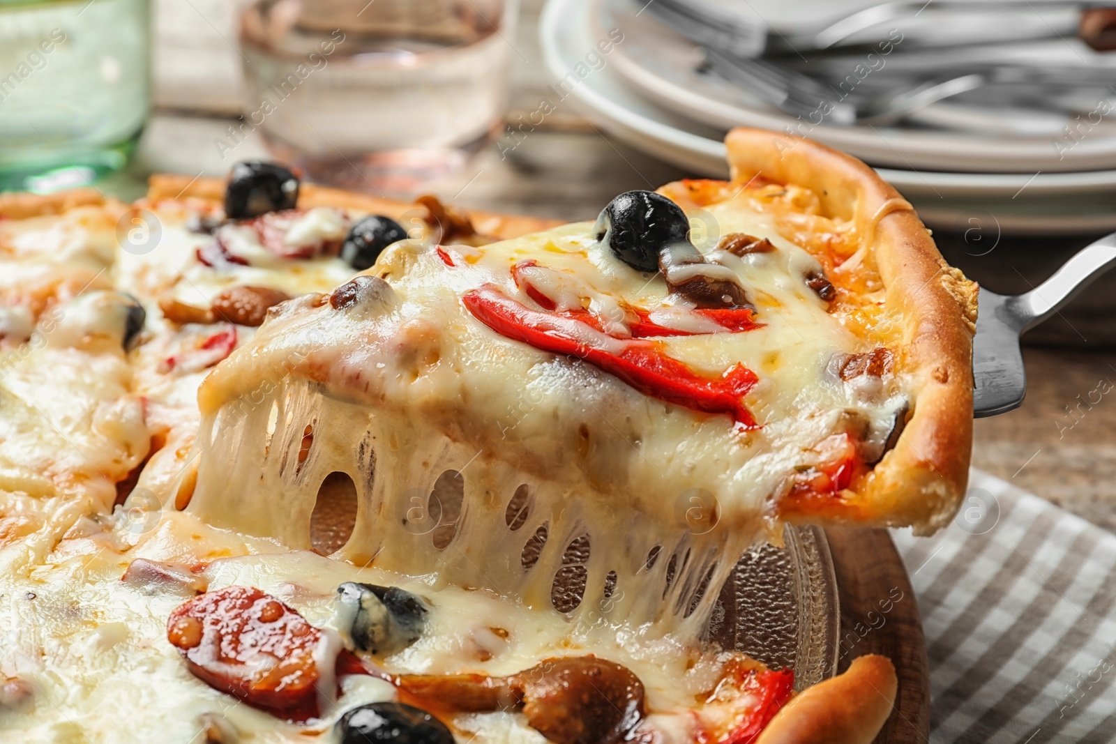 Photo of Shovel with slice of delicious hot pizza over table, closeup