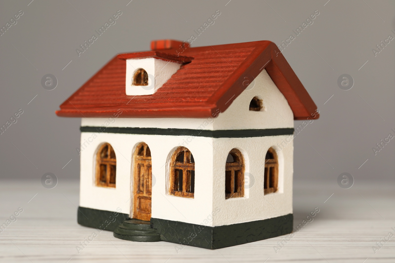 Photo of Mortgage concept. House model on white wooden table against grey background