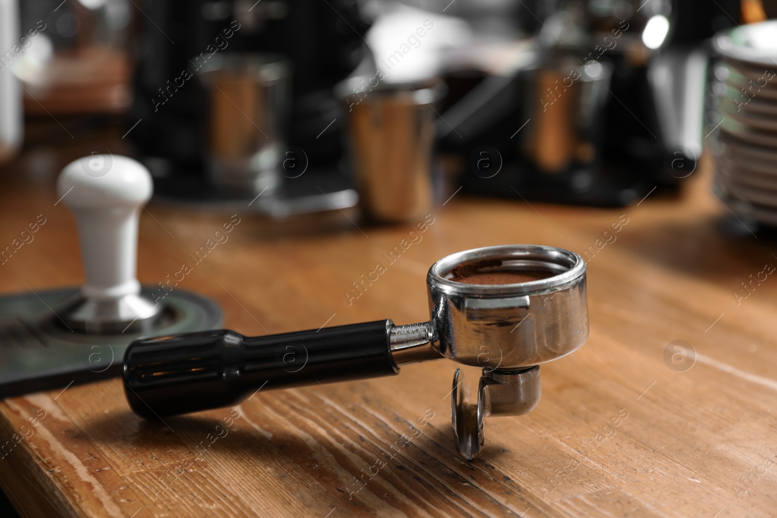 Photo of Portafilter with milled coffee on wooden bar counter. Space for text