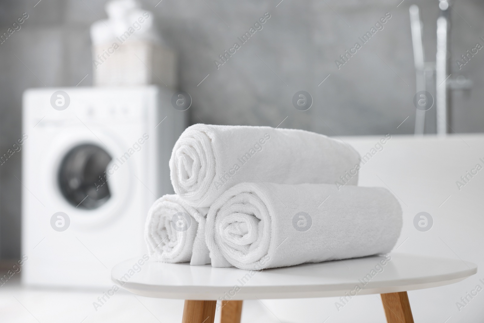 Photo of Rolled white towels on stool in bathroom