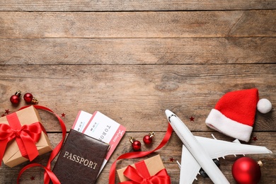 Photo of Flat lay composition with Christmas decorations, passport and airline tickets on wooden table, space for text. Winter vacation