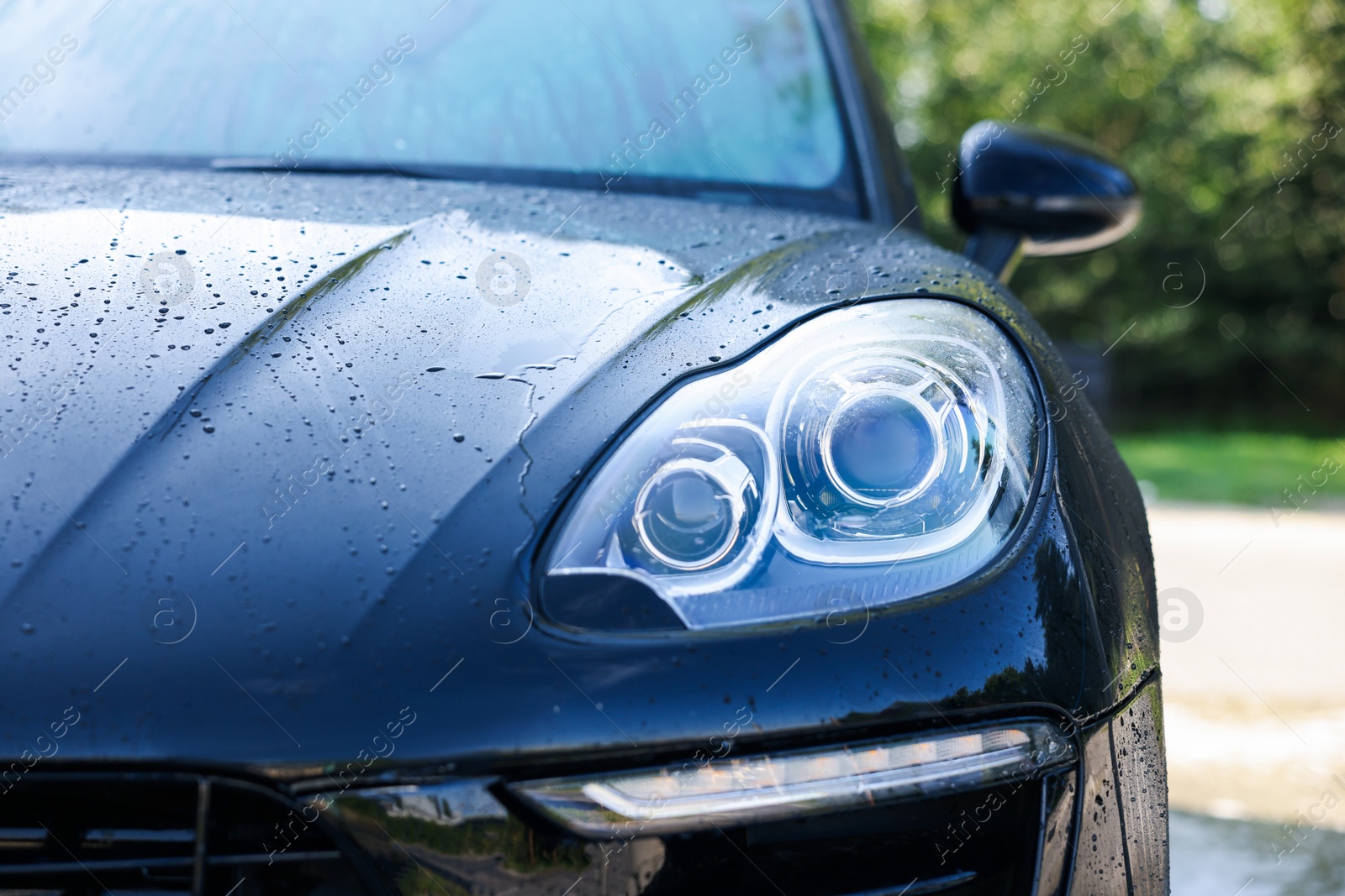 Photo of Clean auto after washing at outdoor car wash, closeup