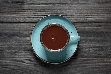 Yummy hot chocolate in cup on black wooden table, top view