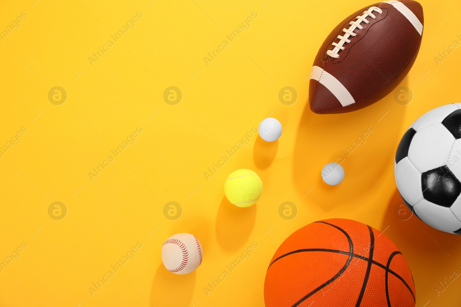 Photo of Many different sports balls on yellow background, flat lay. Space for text
