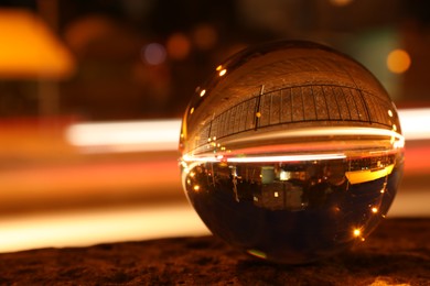 Photo of Beautiful city street, overturned reflection. Crystal ball at night, closeup. Space for text