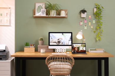 Photo of Stylish workplace with computer, laptop and lamp near olive wall at home