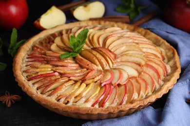 Photo of Delicious homemade apple tart with mint on black table