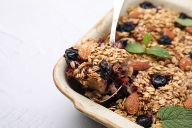 Photo of Tasty baked oatmeal with berries and almonds in baking tray on white table, closeup