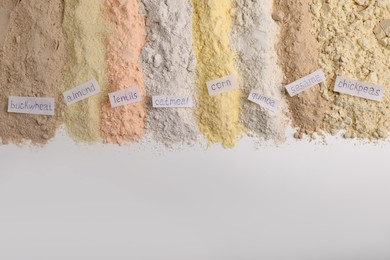 Photo of Different types of flours on white background, flat lay. Space for text