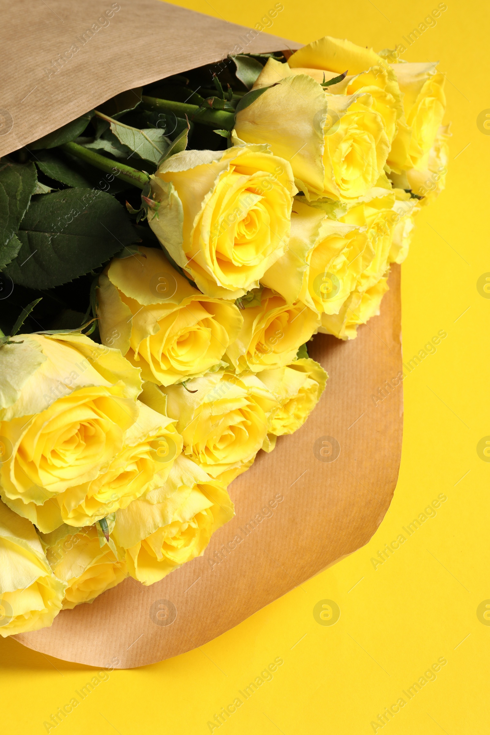 Photo of Beautiful bouquet of roses on yellow background, above view