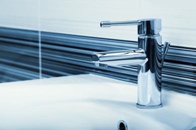 Image of Clean white sink with shiny water tap in bathroom