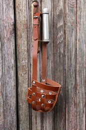Photo of Brown dog muzzle hanging near wooden fence