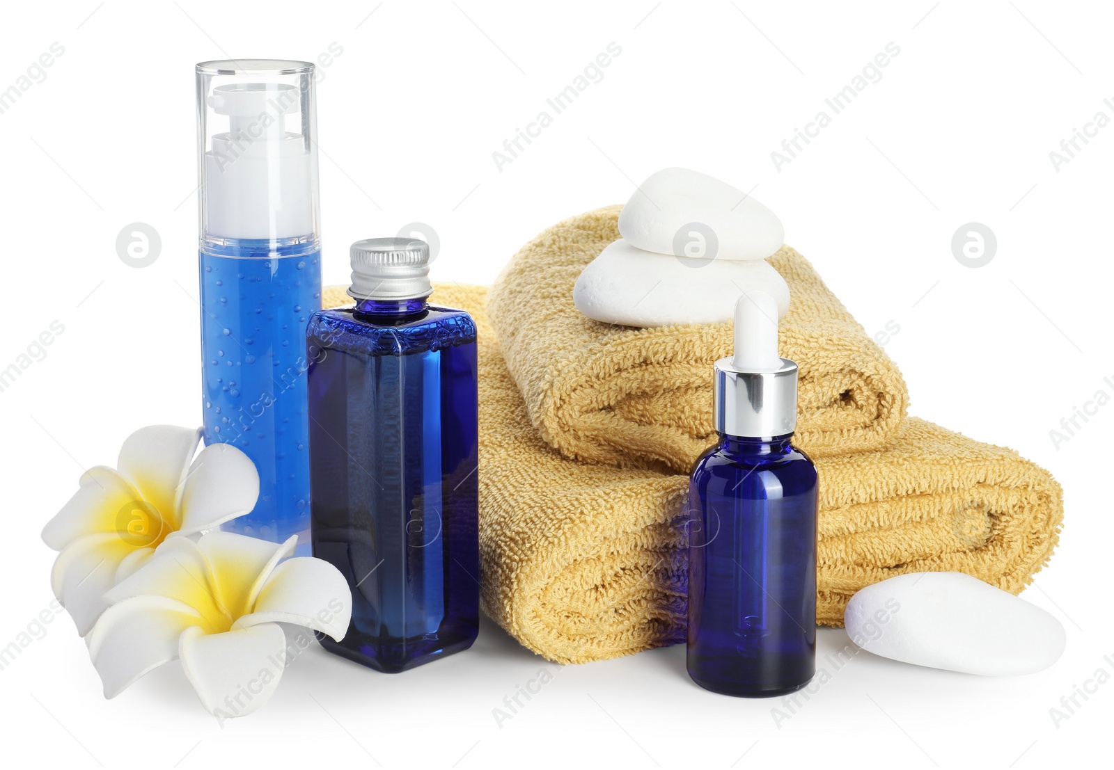 Photo of Spa composition. Bottles of cosmetic products, towels, stones and plumeria flowers isolated on white