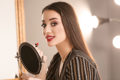 Photo of Portrait of beautiful woman applying makeup indoors