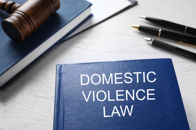 Photo of Domestic violence law on white wooden table, closeup