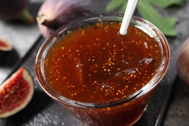Photo of Glass bowl with tasty fig jam on table, closeup