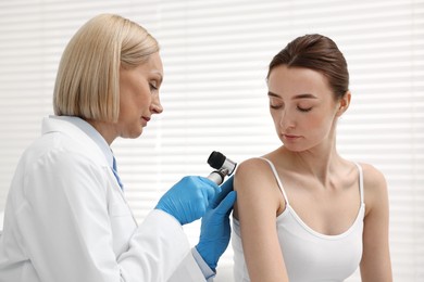 Photo of Dermatologist with dermatoscope examining patient in clinic