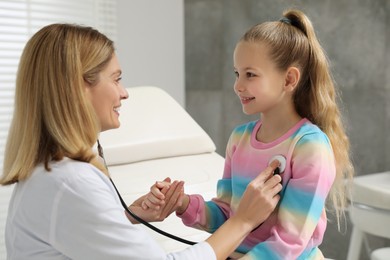 Photo of Pediatrician examining little patient with stethoscope in clinic