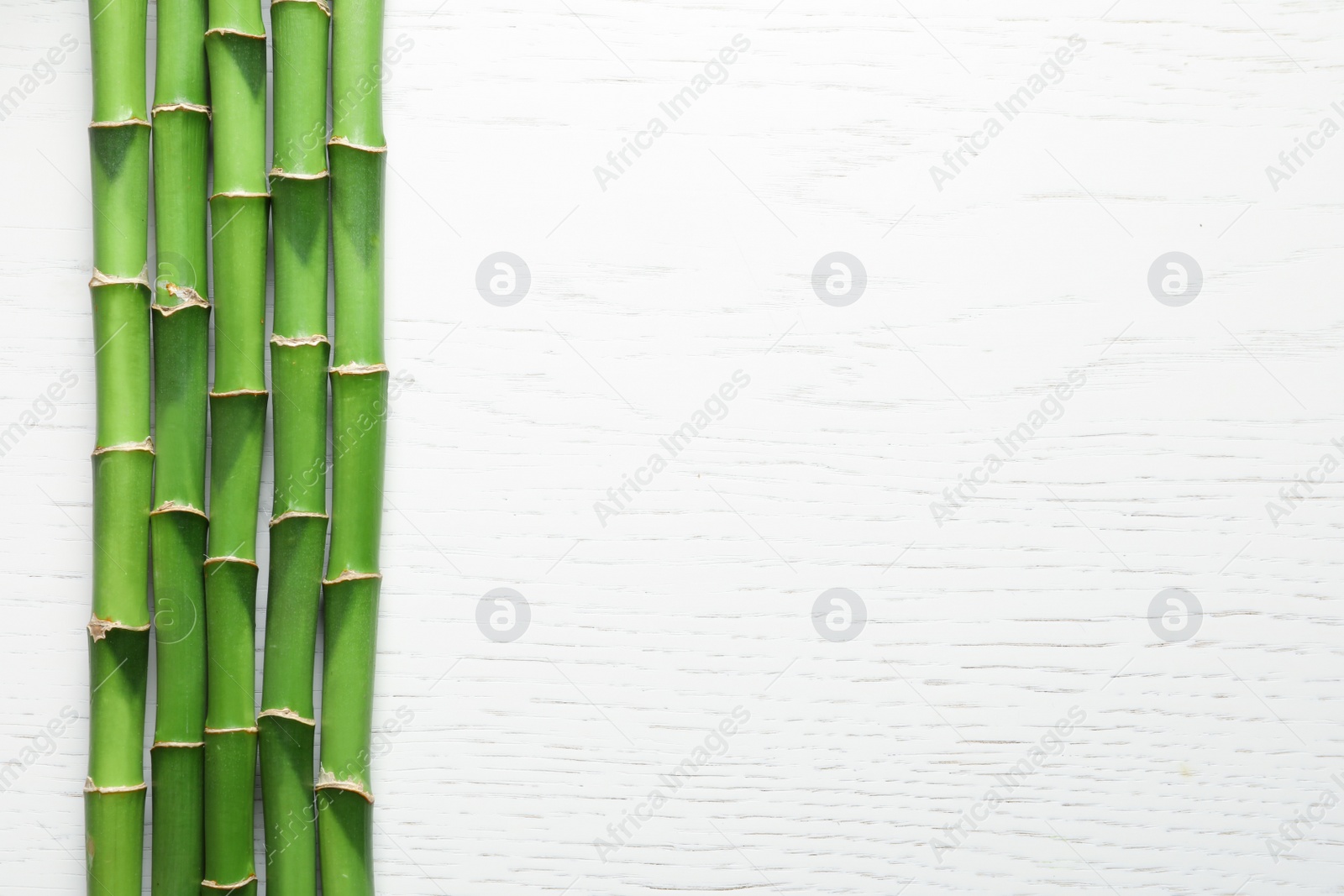 Photo of Green bamboo stems and space for text on wooden background, top view