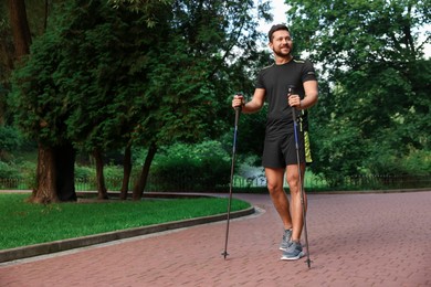 Photo of Man practicing Nordic walking with poles outdoors. Space for text