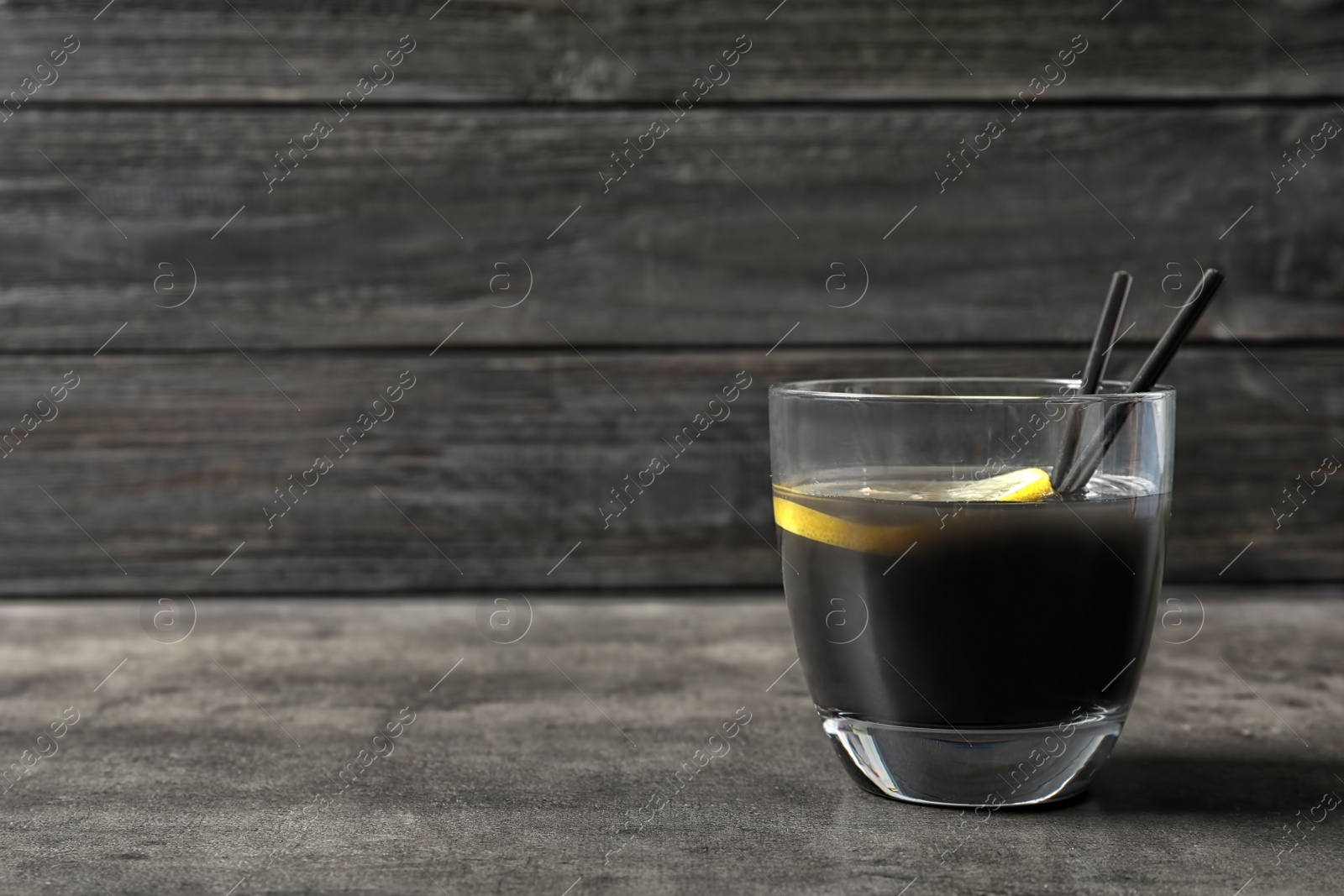 Photo of Glass with natural black lemonade on table