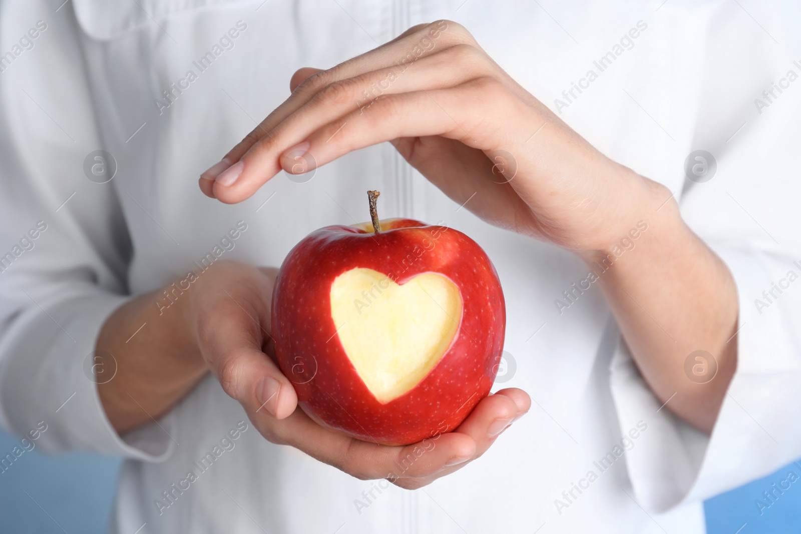 Photo of Woman holding apple with carved heart, closeup