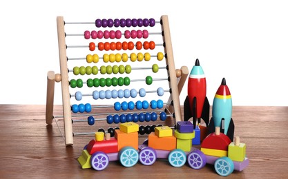 Photo of Bright toy train, abacus and rockets on wooden table against white background